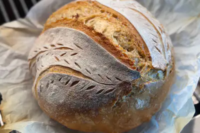A round sourdough loaf with decorative leaf scoring