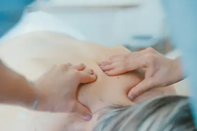 A therapist’s hands working on the muscles of a woman’s upper back