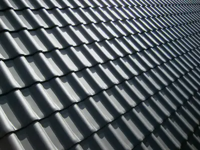 Neat rows of dark grey roof tiles in bright sunlight