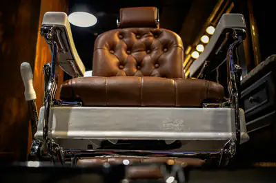 A tan leather barber’s chair with a chrome frame