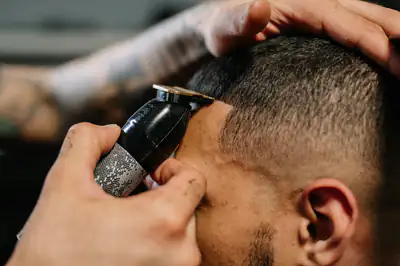 Close-up of clippers lining up a fade above the ear