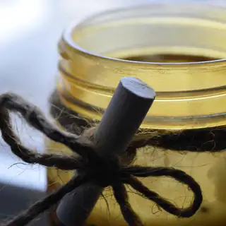 An amber glass candle jar tied with twine around a wooden tag